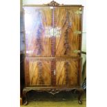 A flame mahogany crossbanded cocktail cabinet, with two pairs of cupboard doors, cabriole legs and