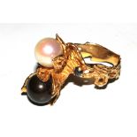 A gold colour metal ring set with black and white cultured pearls and a sapphire to each shoulder