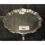 A small silver salver with gadrooned edge on three feet, London 1865