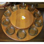 A teak circular Lazy Susan with ten smoked glass dishes, 47cm diameter