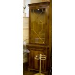 A crossbanded yewwood veneer corner cabinet, the dentil cornice over a glazed door and panelled door