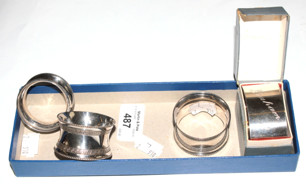 A silver boxed napkin ring and two plated napkin rings and another silver napkin ring