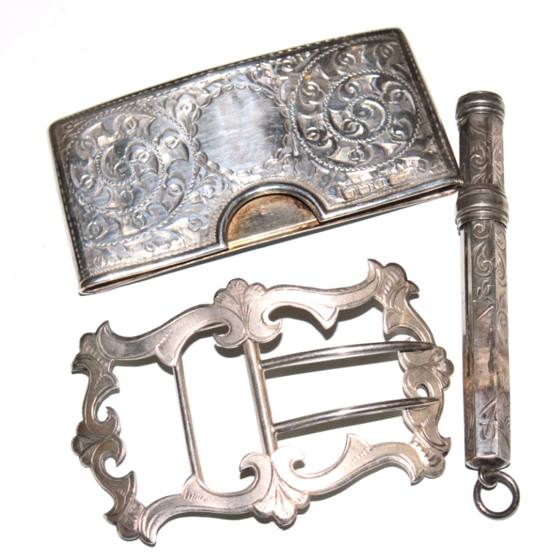 A silver card holder, a silver buckle and a silver pencil, as found