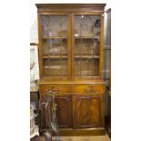 A reproduction George III style mahogany bookcase cabinet, the dentil cornice over glazed doors, two