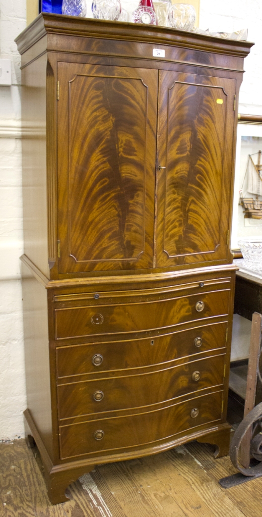 A flame mahogany serpentine side cabinet, with panelled doors over a slide, drawer and cupboard door