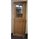 A pine corner cupboard, with glazed doors over a panelled door, 169cm high