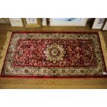 A pair of Kashmir rugs, the red fields with allover foliate design and ivory medallions, within