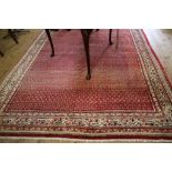 A Persian Sarouk Mir carpet, the red field with all over pattern within a multiple ivory border,