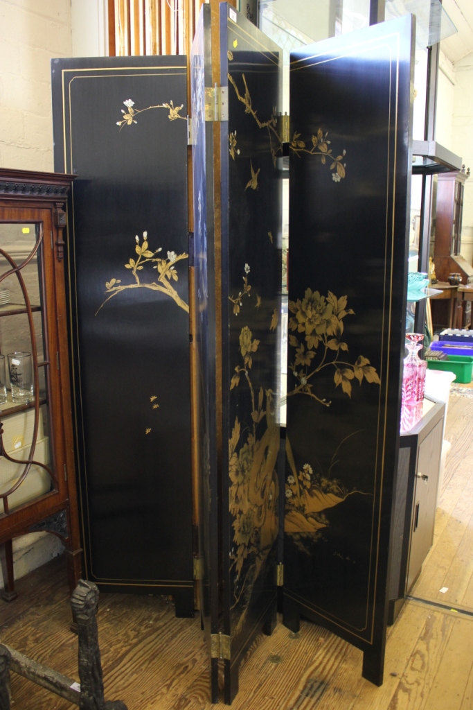 A black lacquered four fold screen, with gilt decoration of birds on blossoming branches, each panel