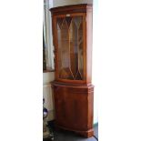 A yewwood veneer bowfront corner cabinet, the dentil cornice over a glazed door above an oval
