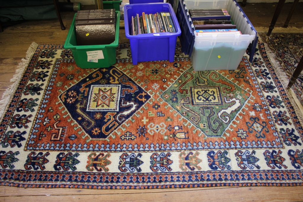 An Indian Kazak style rug, the blue and green medallions on a rust field with ivory borders, 192cm x