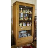 An oak Riva Colonia display cabinet, the glazed door enclosing shelves and two drawers, above two