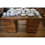 A teak kneehole desk, the laminated top over two banks of shaped drawers and panel sides on cabriole