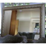 A silver coloured painted wall mirror, with bevelled plate and foliate carving, 76cm x 95cm