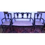 An Edwardian ebonised three piece drawing room suite, the shaped top rails over vase shape splats