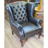 A brown leather wing armchair, with cabriole legs