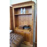 A pine open bookcase, with adjustable and pull-out shelves over a pair of cupboard doors, 114cm