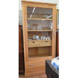 An oak Riva Colonia display cabinet, the glazed door enclosing shelves and two drawers, above two