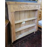 A pine wall rack, the acorn carved frieze over three shelves with reeded supports, 103cm wide