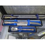 A bread knife, a cake knife and a preserve spoon, all boxed all with silver handles