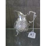 A late continental silver cream jug decorated in relief