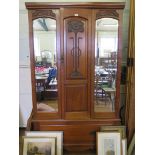 A late Victorian walnut wardrobe, the reduced cornice over a carved panel door flanked by mirrors on