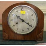 A 1920's walnut cased mantel clock, with foliate carved corners, the silvered dial enclosing a