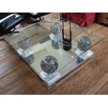 A glass top coffee table, with marble effect globular supports mirrored base and perspex stepped