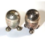 A pair of silver pepperettes on three ball feet