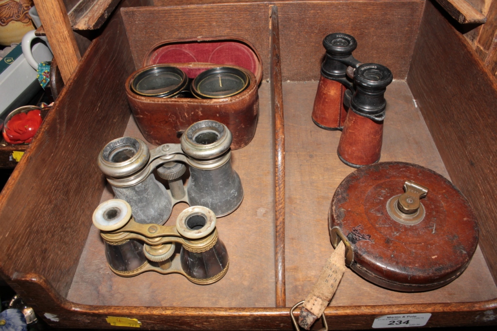 A pair of mother of pearl and brass opera glasses, three other pairs and a 66ft fabric tape