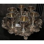 A silver plated egg cup stand with six egg cups and six silver spoons