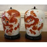 A pair of Chinese ginger jars, with later wooden lids, depicting dogs and puppies in red with some