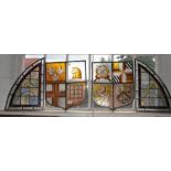 A pair of shield shape leaded stained glass windows, the quarters painted with heraldic emblems,