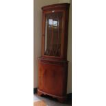 A yewwood veneer bowfront corner cabinet, the dentil cornice over a glazed door above an oval