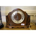 A 1920's walnut mantel clock, the shaped case with sunburst motifs and silvered dial enclosing a