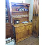 A pine dresser and rack, the base with two drawers and two cupboard doors on a plinth base, 107cm