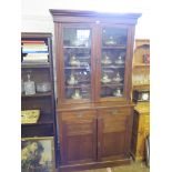 An Edwardian walnut bookcase cabinet, the moulded cornice over a pair of glazed doors, the base with