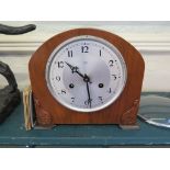 A 1920's walnut cased mantel clock, with foliate carved corners, the silvered dial enclosing a