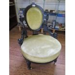A late Victorian ebonised nursing chair, the oval back on turned and scroll supports, above turned
