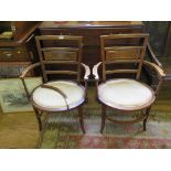 A pair of Edwardian mahogany open armchairs with boxwood stringing, the backs with trophy and swag