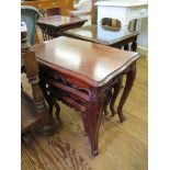A nest of three mahogany French style tables, the shaped tops over fleurs de lys carved friezes