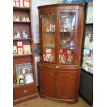 A pair of yew wood corner display cabinets, each with dentil cornice over a pair of glazed doors and