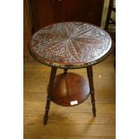 A carved wood tripod table, the circular top carved with flowers and lunette's on turned legs joined