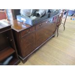 A reproduction crossbanded mahogany sideboard, with three frieze drawers over four doors on