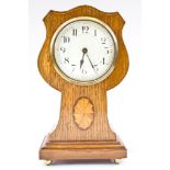 An Edwardian oak and boxwood strung mantel timepiece, the shield shaped waisted case with inlaid