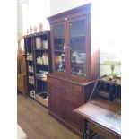 An Edwardian walnut bookcase cabinet, the moulded cornice over a pair of glazed doors, the base with