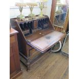 An oak panelled bureau, the sloping fall above two short and one long drawer on turned tapering legs