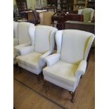 A pair of upholstered wing armchairs, on cabriole legs with club feet (2)