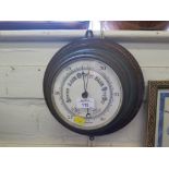 An oak and brass aneroid barometer, circular with ceramic dial, 28cm diameter