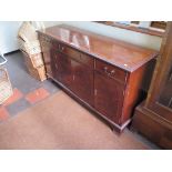 A reproduction crossbanded mahogany sideboard, with three frieze drawers over four doors on